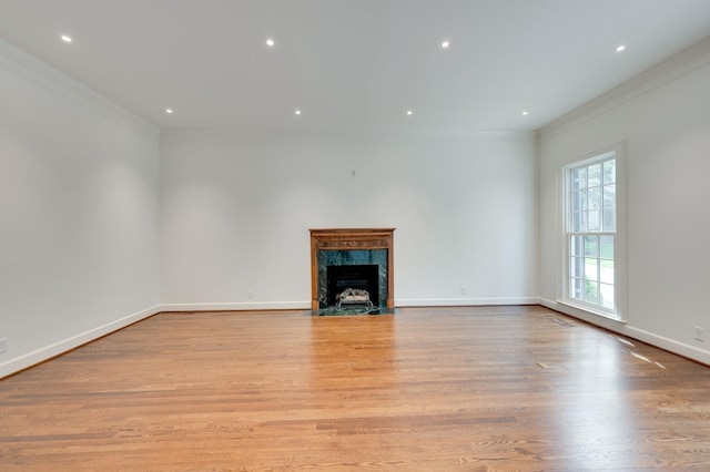 unfurnished living room featuring crown molding, a fireplace, recessed lighting, light wood-type flooring, and baseboards