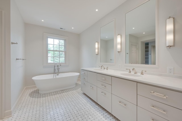 bathroom with a freestanding tub, a sink, baseboards, and double vanity