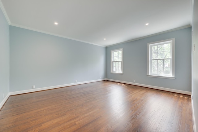 spare room with ornamental molding, wood finished floors, and baseboards