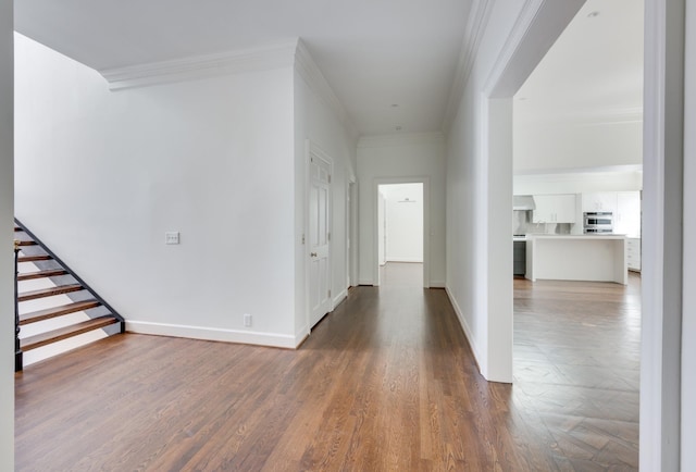 entryway featuring baseboards, wood finished floors, stairs, and crown molding