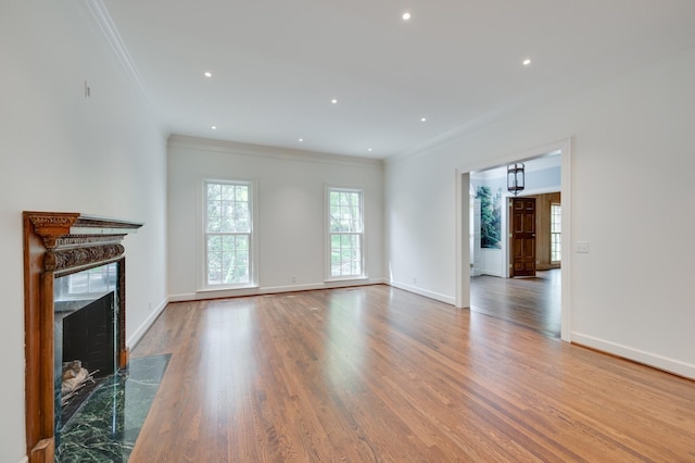 unfurnished living room featuring baseboards, a fireplace, ornamental molding, and wood finished floors