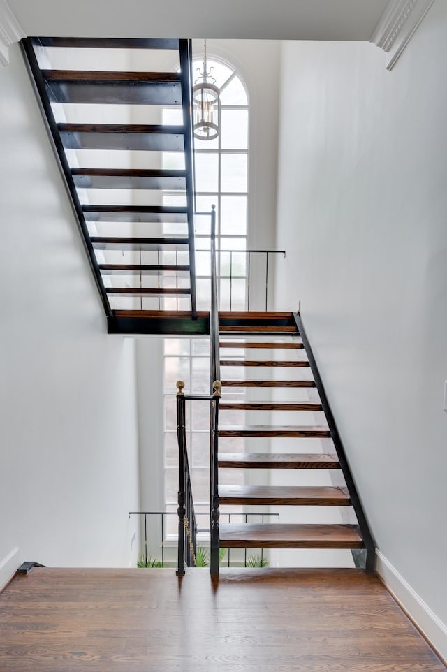 staircase with a chandelier and wood finished floors