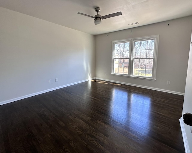 empty room featuring dark wood-style floors, baseboards, visible vents, and a ceiling fan