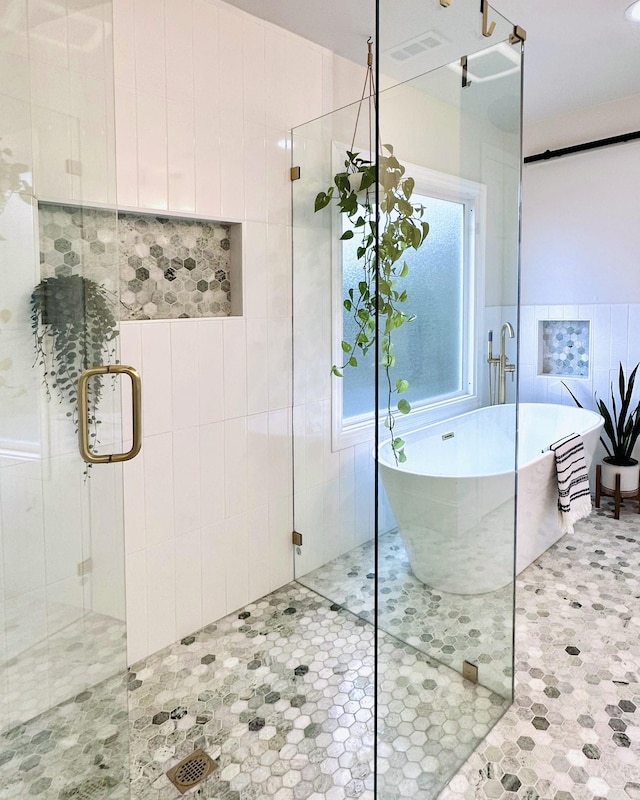 bathroom featuring tile walls, a freestanding tub, visible vents, and a shower stall