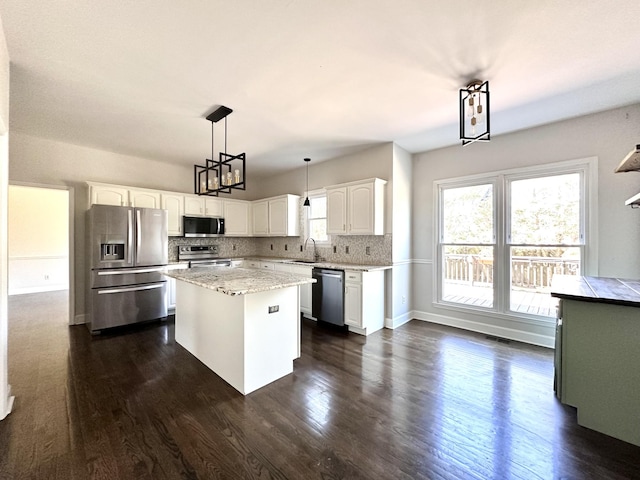 kitchen featuring tasteful backsplash, white cabinets, dark wood-style floors, appliances with stainless steel finishes, and a sink