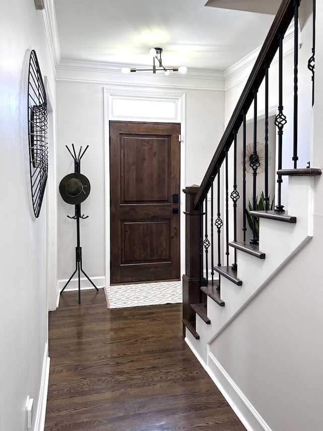 foyer entrance with stairs, crown molding, baseboards, and wood finished floors