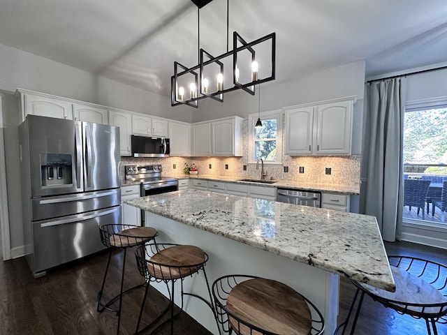 kitchen with appliances with stainless steel finishes, backsplash, a sink, and white cabinets