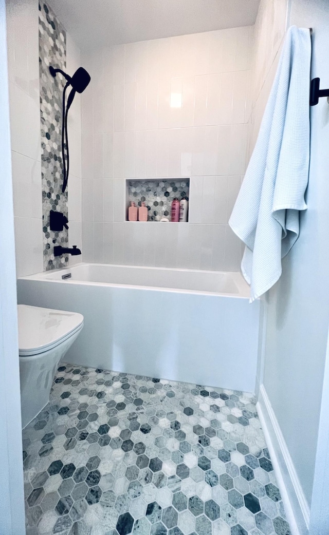 bathroom with baseboards, shower / bath combination, and toilet