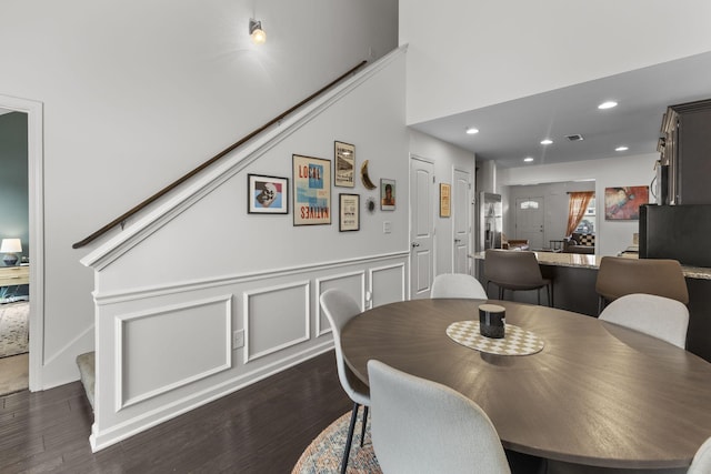 dining room featuring dark wood-type flooring, stairway, recessed lighting, and a decorative wall