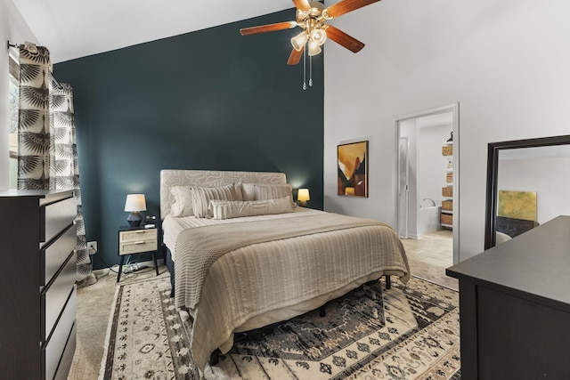 carpeted bedroom with high vaulted ceiling, ceiling fan, baseboards, and ensuite bathroom