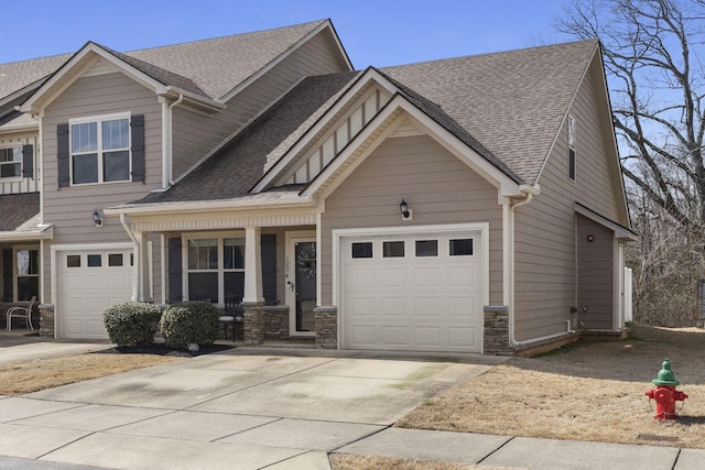 view of front of property with a shingled roof, stone siding, driveway, and an attached garage