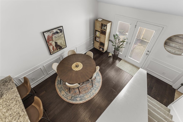 dining space with a wainscoted wall, stairs, a decorative wall, and dark wood finished floors