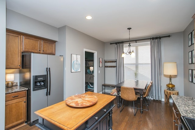 kitchen featuring dark wood-type flooring, electric stove, brown cabinets, stainless steel fridge, and decorative light fixtures