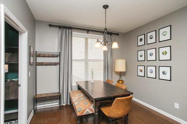 dining area featuring dark wood-style flooring, a notable chandelier, and baseboards