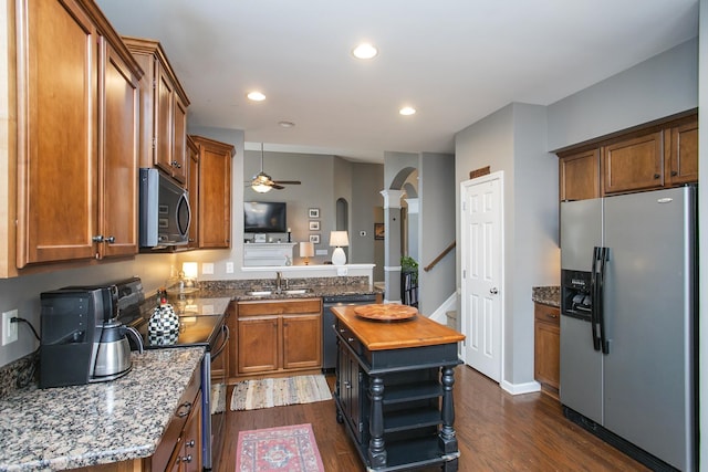 kitchen featuring arched walkways, appliances with stainless steel finishes, dark wood-type flooring, and a sink