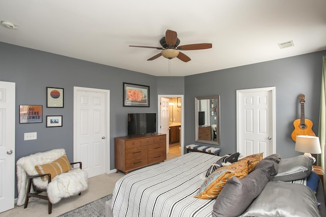 bedroom with light carpet, ensuite bathroom, visible vents, and a ceiling fan