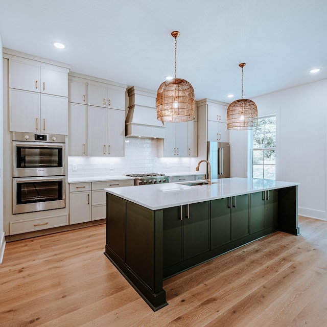 kitchen with premium range hood, a sink, light countertops, appliances with stainless steel finishes, and light wood-type flooring