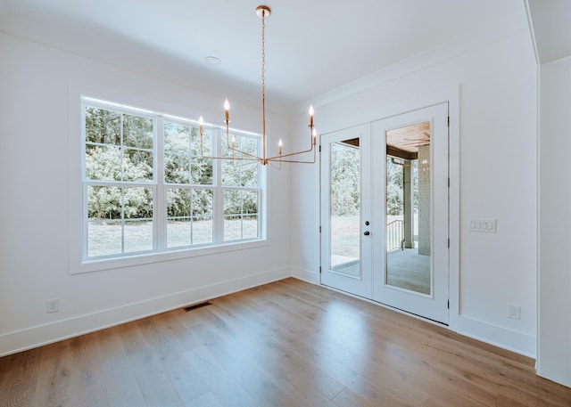 unfurnished dining area featuring baseboards, visible vents, and wood finished floors