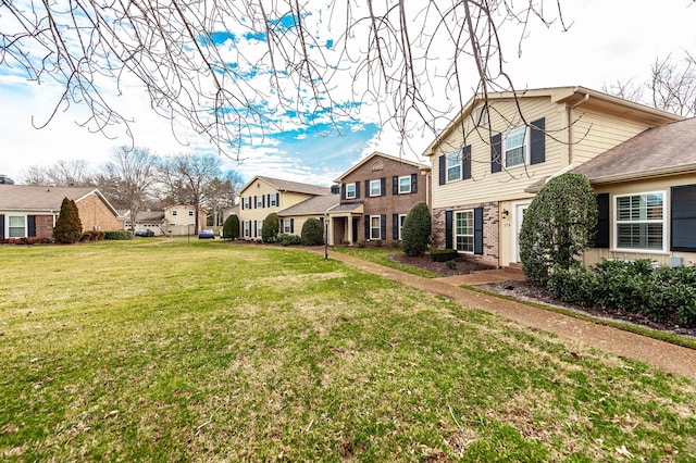 view of front of property featuring a residential view, brick siding, and a front lawn