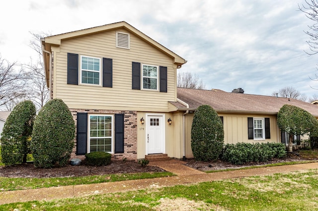 traditional home featuring board and batten siding, brick siding, and a shingled roof