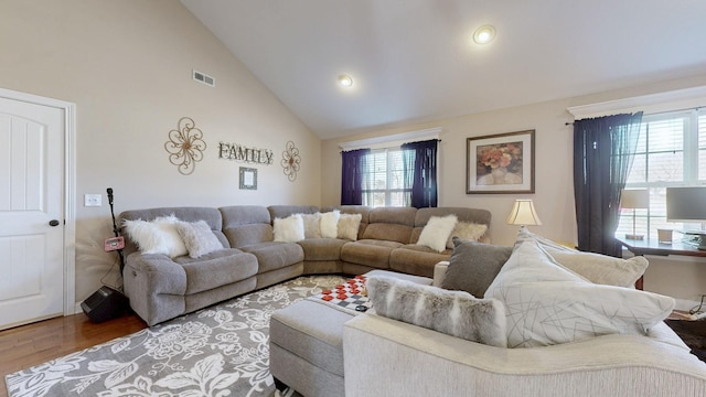 living room featuring a healthy amount of sunlight, high vaulted ceiling, visible vents, and wood finished floors