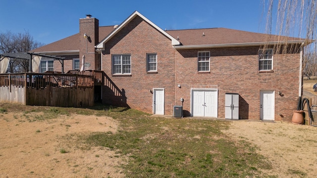 back of property with brick siding, a yard, and a chimney