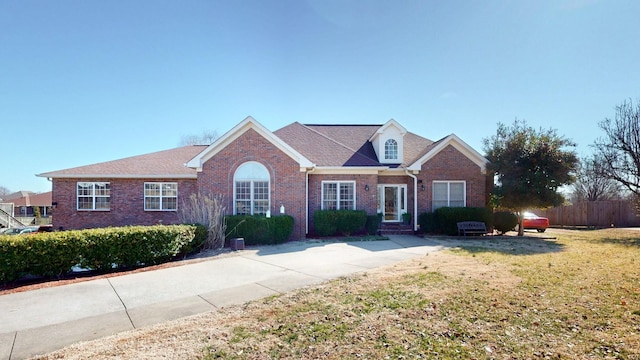 view of front of house featuring a front lawn, fence, and brick siding