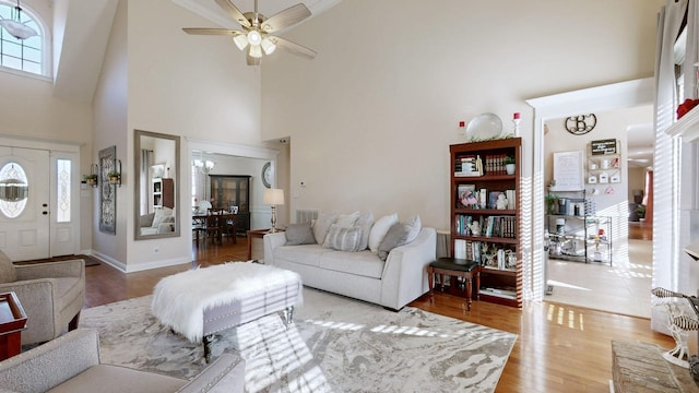 living room featuring ceiling fan, a high ceiling, and light wood-style flooring