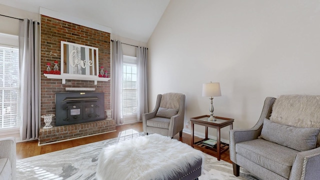 sitting room featuring a wood stove, baseboards, vaulted ceiling, and wood finished floors