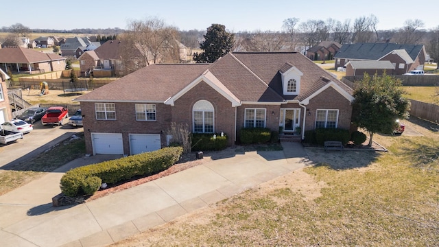 view of front of home with brick siding, an attached garage, fence, a residential view, and driveway