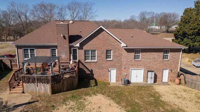 rear view of house featuring fence private yard, brick siding, and a wooden deck