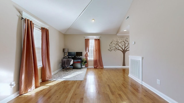 home office featuring light wood-type flooring, baseboards, visible vents, and lofted ceiling