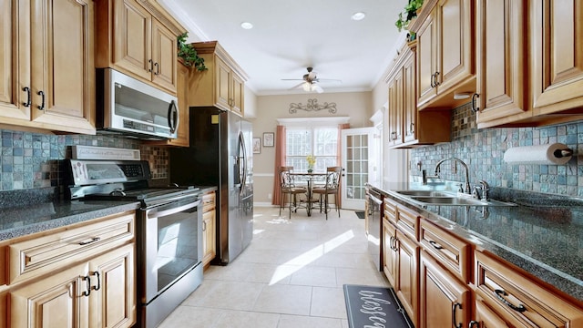 kitchen with light tile patterned floors, ceiling fan, appliances with stainless steel finishes, ornamental molding, and a sink