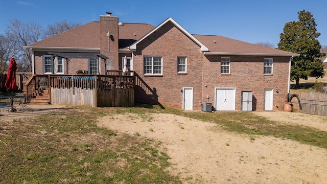 back of property featuring cooling unit, brick siding, fence, a wooden deck, and a chimney