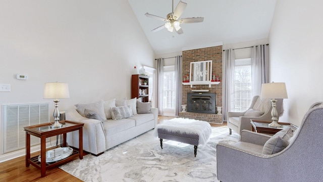 living area with visible vents, a brick fireplace, ceiling fan, wood finished floors, and high vaulted ceiling