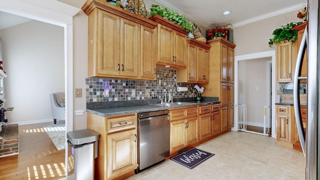 kitchen with appliances with stainless steel finishes, dark countertops, crown molding, and a sink