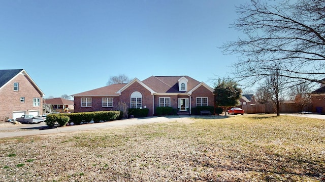 view of front facade with brick siding, a front lawn, and fence