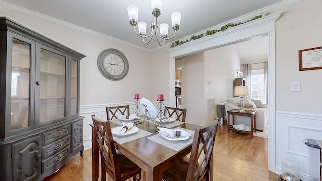 dining space featuring a wainscoted wall, light wood-style floors, and crown molding