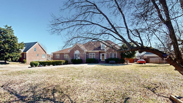 view of front of house with fence, a front lawn, and brick siding