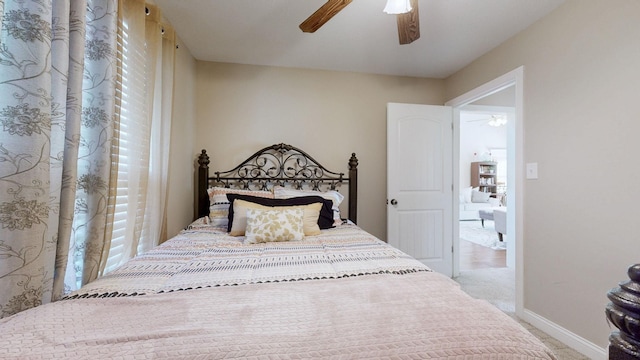 carpeted bedroom with ceiling fan and baseboards