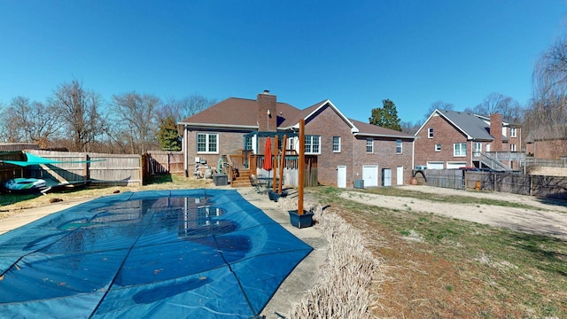 back of house with a chimney, a patio area, a fenced backyard, and a fenced in pool