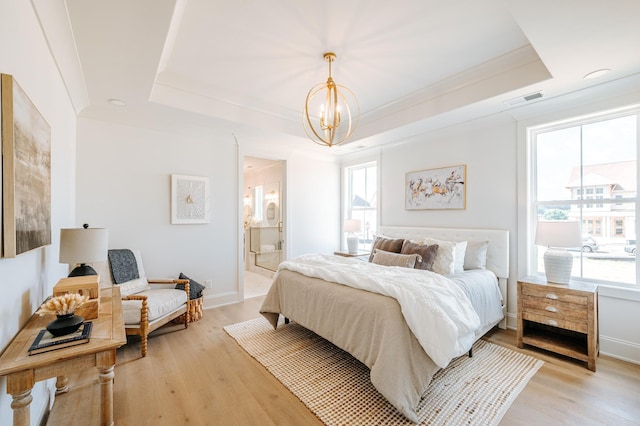 bedroom with a notable chandelier, visible vents, light wood-style floors, a raised ceiling, and crown molding