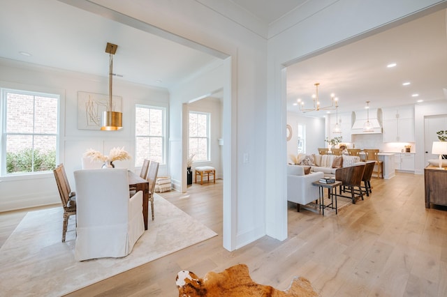 dining room with baseboards, light wood-style flooring, ornamental molding, an inviting chandelier, and recessed lighting