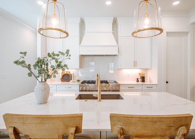 kitchen with decorative light fixtures, crown molding, tasteful backsplash, custom range hood, and white cabinets