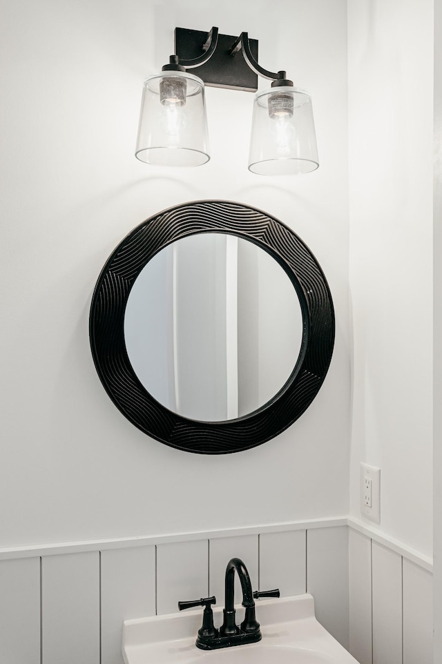 room details featuring a wainscoted wall, a decorative wall, and a sink