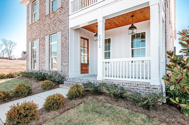 view of exterior entry with covered porch and brick siding