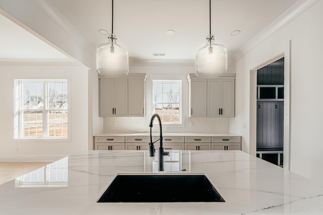 kitchen featuring light stone countertops, a sink, visible vents, and crown molding