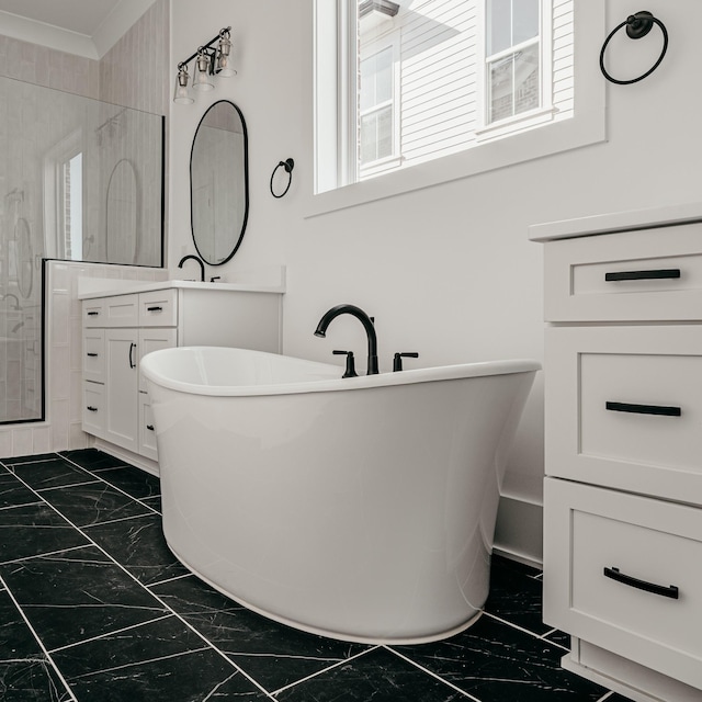 bathroom with marble finish floor, a freestanding tub, and vanity