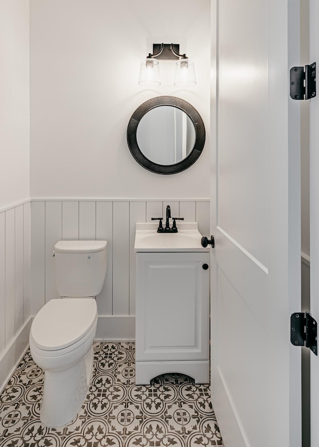 bathroom featuring tile patterned flooring, a wainscoted wall, vanity, and toilet