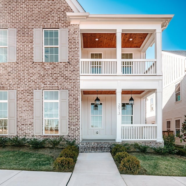 view of front of home with a porch, board and batten siding, a balcony, and brick siding